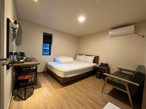 een kleine kamer met een bed, een bureau en een stoel bij Ssangma Motel in Busan