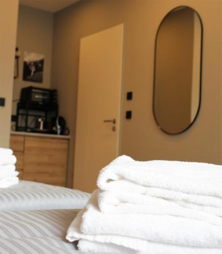a stack of towels on a bed with a mirror at ARRIVEL Apartements Heimstetten - bisher Novitel in Kirchheim