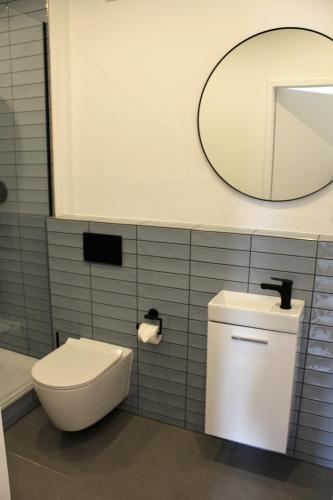 a bathroom with a white toilet and a mirror at ARRIVEL Apartements Heimstetten - bisher Novitel in Kirchheim