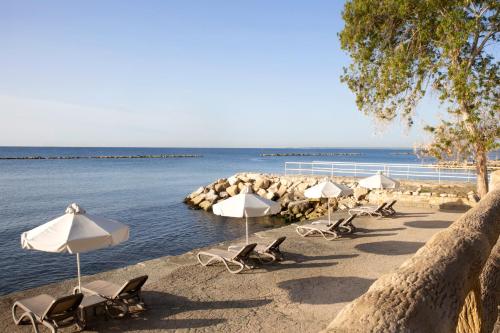 a row of chairs and umbrellas on a beach at Harmony Bay Hotel in Limassol