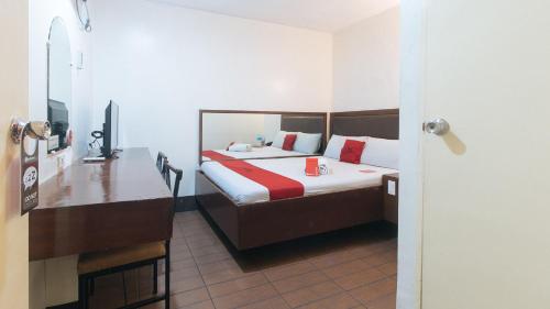 um quarto com uma cama e uma secretária com uma televisão em RedDoorz @ Riches Holiday Hotel Avenida em Manila