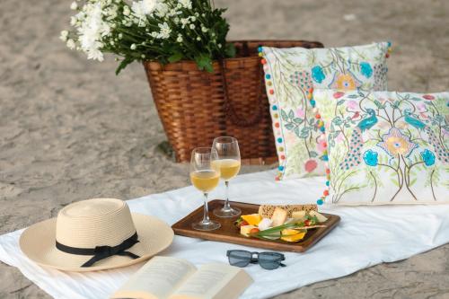 een picknick met glazen wijn, een hoed en een schaal vol eten bij LaRiSa Resort, Morjim in Morjim