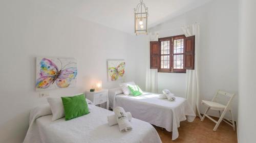 Casa Fuentezuelas Sayalonga by Ruralidays في Sayalonga: غرفة بيضاء بسريرين ونافذة
