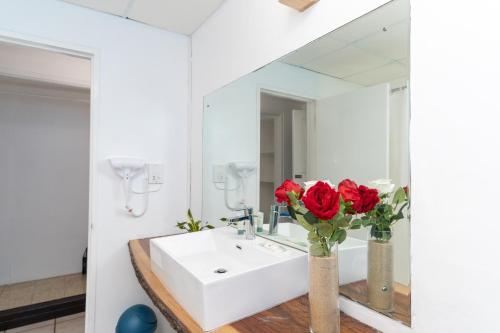 a bathroom with a sink and red roses in vases at Sand and Tan Beach Hotel in Ocho Rios