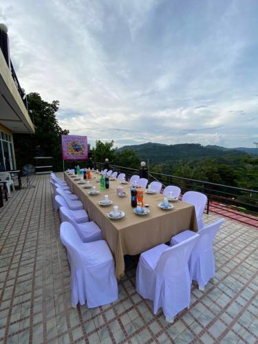 a long table with white chairs and a table at Phuyafahsai The Resort Khao Kho in Khao Kho