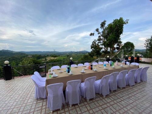 a long table with white chairs and a table at Phuyafahsai The Resort Khao Kho in Khao Kho