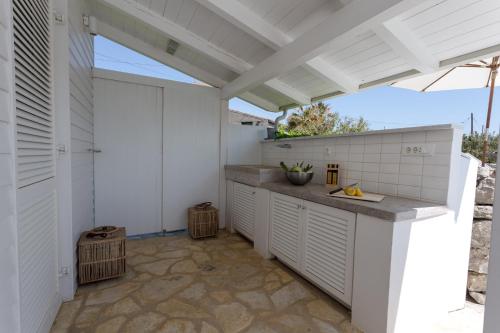 an outdoor kitchen with white cabinets and awning at PAVI APARTMENTS Life Style House with private pool in Kornić