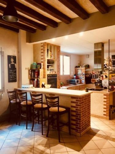 Il comprend une cuisine avec un bar et des chaises. dans l'établissement Superbe maison de caractère, de 1 à 9 couchages, à Sainte-Maure-de-Touraine