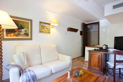 a living room with a white couch and a television at Hotel Cala Sant Vicenç - Adults Only in Cala de Sant Vicent