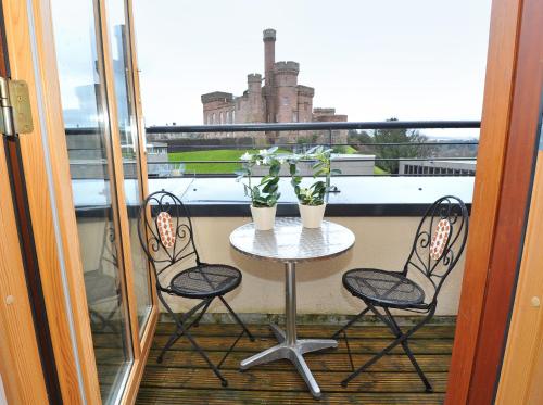 a table with two chairs and two plants on a balcony at Highland Apartments by Mansley in Inverness