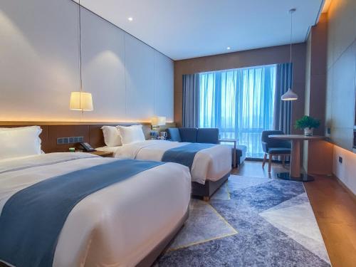 um quarto de hotel com duas camas e uma secretária em Howard Johnson by Wyndham Lanting Hotel Ningbo em Ningbo