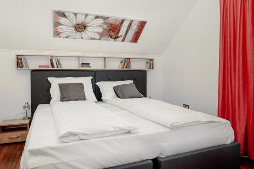 a bedroom with a large white bed with a red curtain at Coolis Apartments Șirul Livezii in Braşov