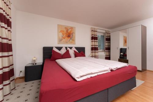 sypialnia z dużym łóżkiem z białymi i czerwonymi poduszkami w obiekcie Appartement Imelda w mieście Umhausen