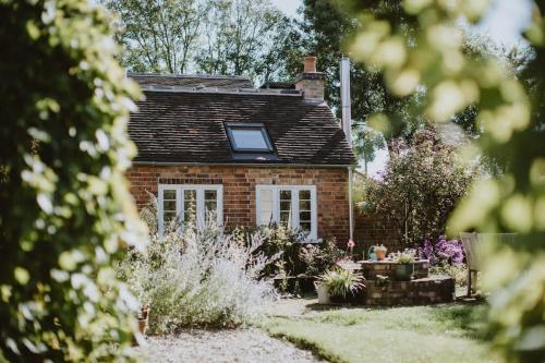 a small brick house with a window in a garden at The Barn in Nottingham