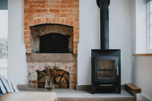 a brick fireplace with a vase of flowers in front of it at The Barn in Nottingham