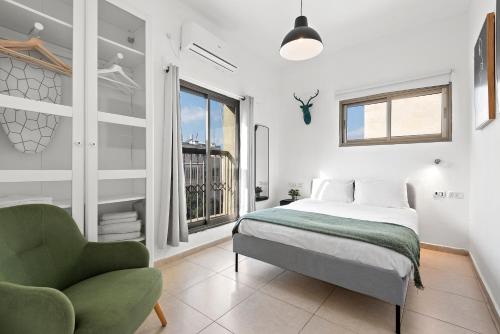 um quarto com uma cama, uma cadeira e uma janela em Design Apartments em Tel Aviv
