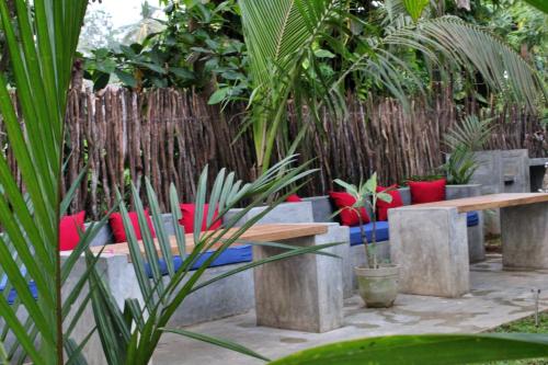 a garden with benches and red pillows and a fence at Pranaya Hiriketiya in Hiriketiya