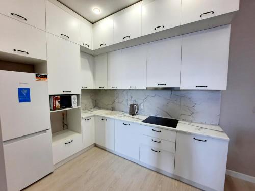 eine weiße Küche mit weißen Schränken und weißen Geräten in der Unterkunft Исы Байзакова 131, новостройка in Pawlodar