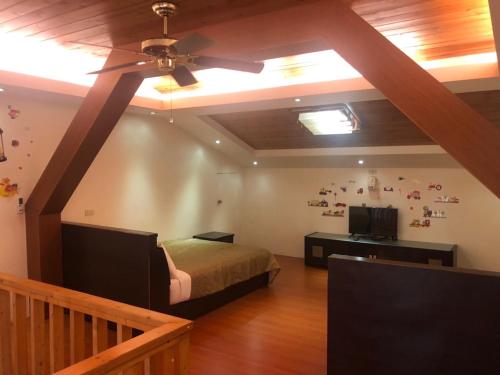 een slaapkamer met een bed en een plafondventilator bij Country Homestay in Guoxing