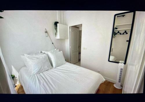 - un lit blanc avec des oreillers blancs et un miroir dans l'établissement Cute one bedroom in Le Marais, à Paris