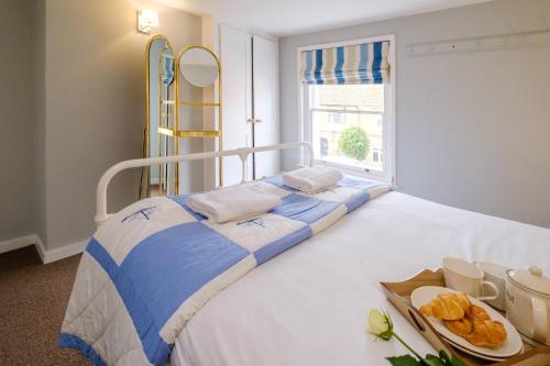 a white and blue bed with a tray of food on it at Sleepers Cottage in Aldeburgh