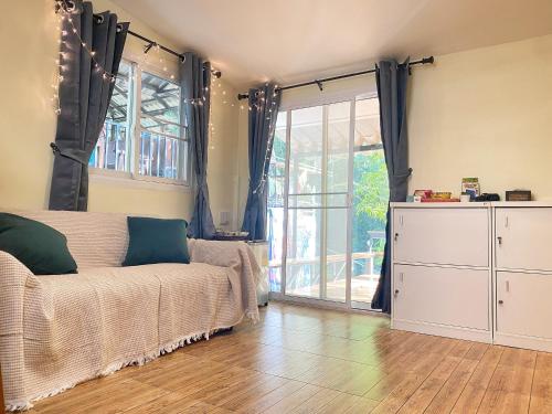 een woonkamer met een bank en een glazen schuifdeur bij Chomklong Experience in Pak Chong