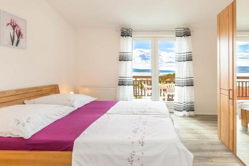 een slaapkamer met een groot bed met paarse en witte lakens bij Paramount Apartments in Dugi Rat