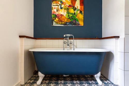 La salle de bains est pourvue d'une baignoire bleue et d'un tableau. dans l'établissement Belle maison contemporaine avec piscine, à Nantes