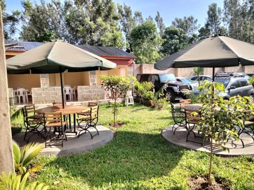 einen Tisch und Stühle mit Sonnenschirmen im Hof in der Unterkunft Good Morning Hotel Rongo in Paulo