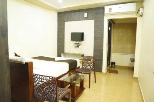 a bedroom with a bed and a table and chairs at Bhimas Residency in Kurmannapalem