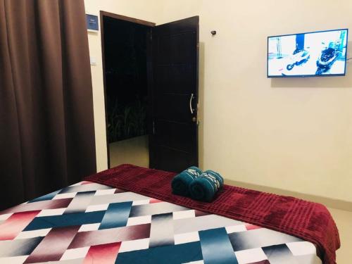 ein Schlafzimmer mit einem Bett und einem TV an der Wand in der Unterkunft Calliandra Homestay in Banyuwangi