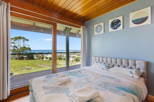 a bedroom with a bed and a large window at Apollo Panorama Guesthouse in Apollo Bay