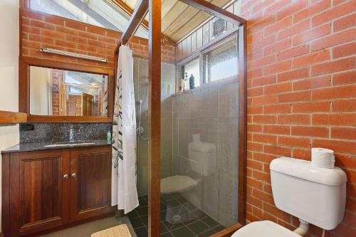 a bathroom with a toilet and a glass shower at Apollo Panorama Guesthouse in Apollo Bay