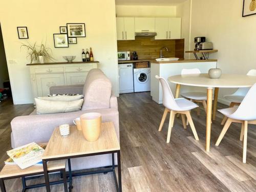 un salon avec un canapé et une table et une cuisine dans l'établissement Le Corton - 45m2 - Parking - Jardin - Wifi, à Cassis