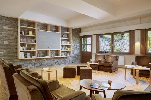 una sala de estar con sillas, mesas y una pared de ladrillo. en Loisach Smarthotel by keyone, en Lermoos
