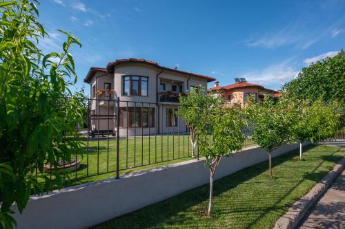 a house with trees in front of a fence at KATERINA guest house in Kocherinovo