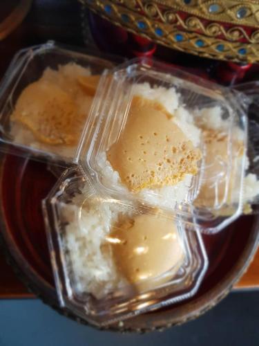 two plastic containers of food on a plate at Ma Guesthouse Chiang Mai in Chiang Mai