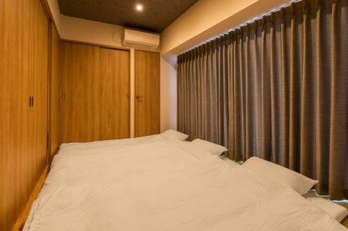 a bedroom with a large white bed in front of a window at LAPIN MIHAMA Residence Hotel in Chatan