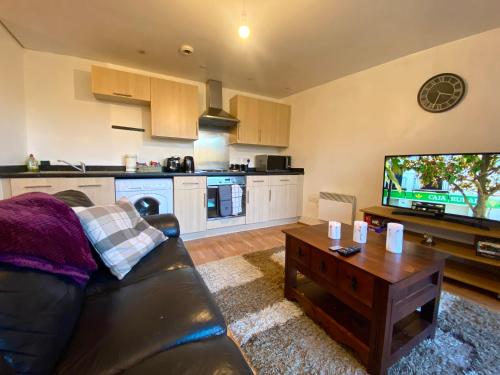 a living room with a black leather couch and a tv at Swanky Central Apartment with Free Wifi (Sleeps 4) in Birmingham
