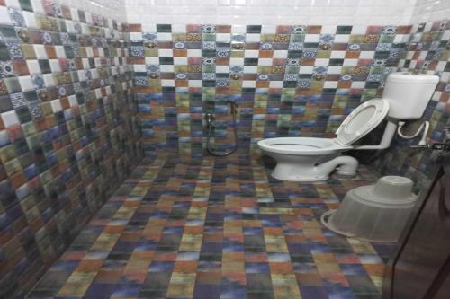 a bathroom with a toilet and a mosaic shower curtain at Bhimas Residency in Kurmannapalem