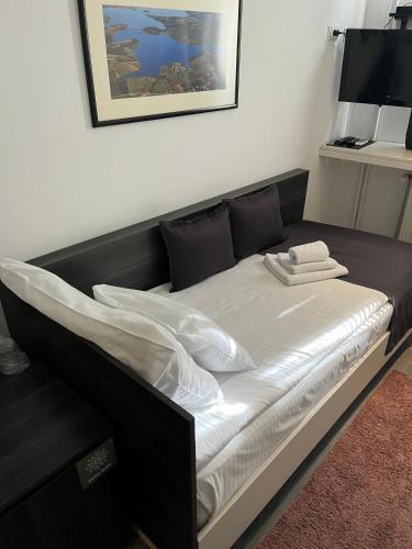 a bed with a black frame and white sheets at Garni hotel King in Kragujevac