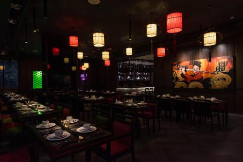a dining room with tables and chairs and chinese lights at Ashley Tang Menteng Jakarta in Jakarta