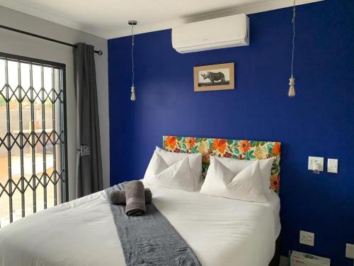 Lion House, 3 bedroom House next to Pilanesberg and Sun City في Mogwase: غرفة نوم زرقاء مع سرير مع ملاءات ووسائد بيضاء