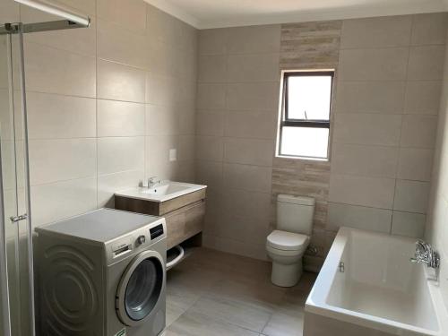 a bathroom with a washing machine and a sink at Lion House, 3 bedroom House next to Pilanesberg and Sun City in Mogwase