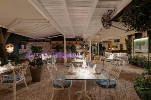 a restaurant with white tables and chairs and plants at Acanthus blue in Corfu Town