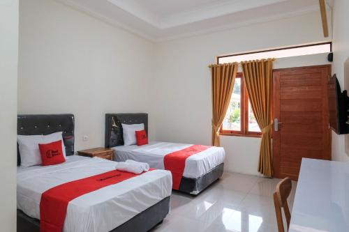 a hotel room with two beds and a window at RedDoorz Plus Syariah at Hotel Indonesia Kajen in Pekalongan