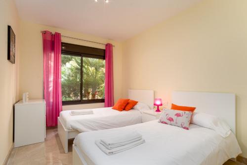 een slaapkamer met 2 bedden en een raam met roze gordijnen bij Duquesa Village 2402 in Manilva