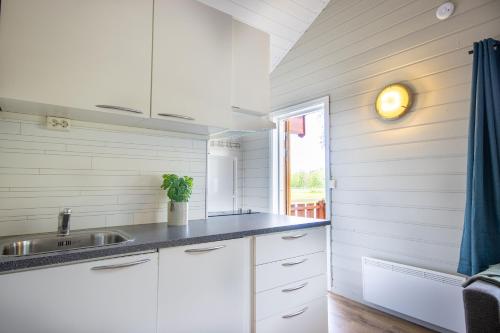 a kitchen with white cabinets and a sink and a window at Topcamp Mosjøen - Helgeland in Mosjøen