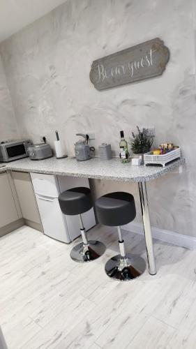 a kitchen counter with two stools under a counter top at Courtyard Holiday Apartments in Belper