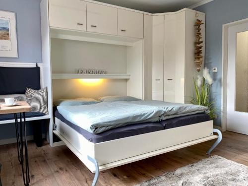 um quarto com uma cama branca e uma secretária em Mein Lieblingsplatz (App.21) em Sankt Peter-Ording